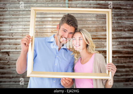 Composite image of young couple holding photo frame Banque D'Images