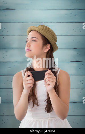 Libre de brunette in hat holding phone Banque D'Images