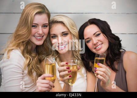 Image composite de pretty friends drinking champagne together Banque D'Images