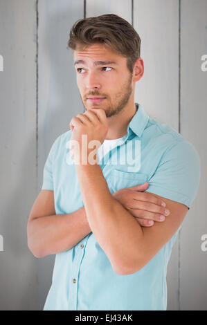 Image composite de handsome young man thinking with hand on chin Banque D'Images