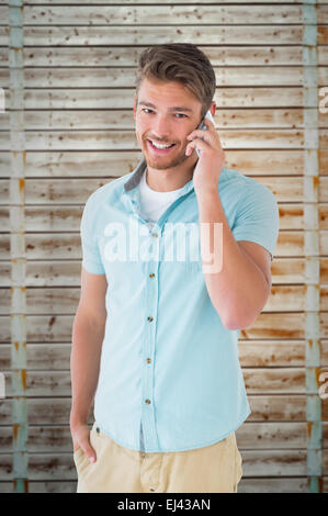 Image composite du beau jeune homme en conversation sur son smartphone Banque D'Images