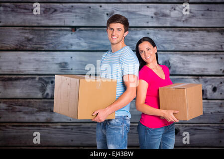 Image composite de young couple holding moving boxes Banque D'Images