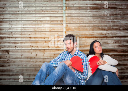 Image composite de young couple sitting on floor with broken heart Banque D'Images