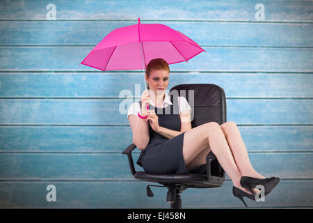 Composite image of businesswoman holding umbrella pointing Banque D'Images