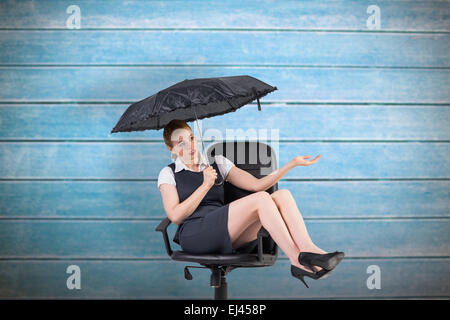 Composite image of businesswoman holding umbrella pointing Banque D'Images