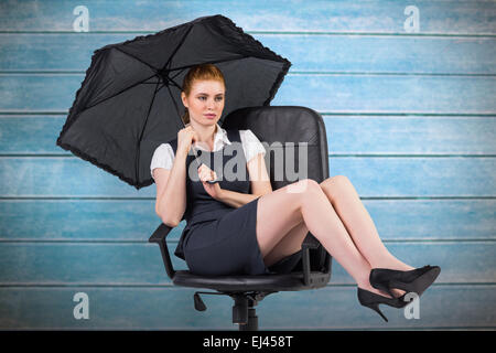 Composite image of businesswoman holding umbrella pointing Banque D'Images