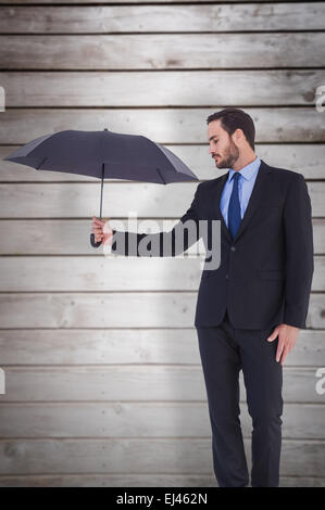 Composite image of businesswoman in suit holding umbrella Banque D'Images