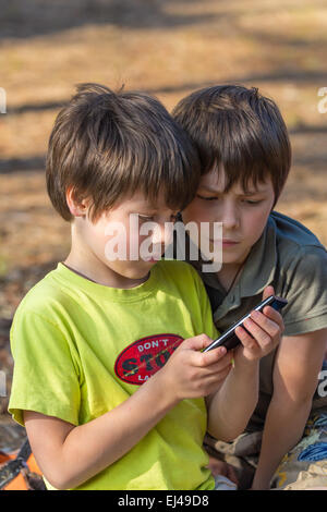 Les enfants deux petits garçons jouant à l'extérieur du téléphone mobile Banque D'Images