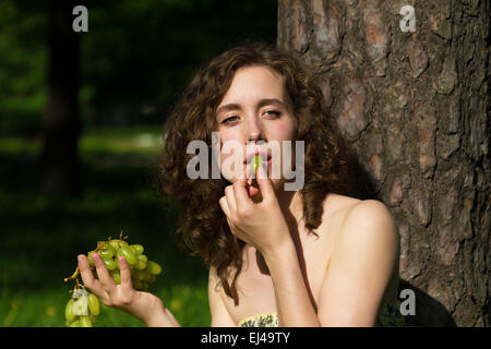 Jolie femme avec snack-raisin snack en plein air Banque D'Images