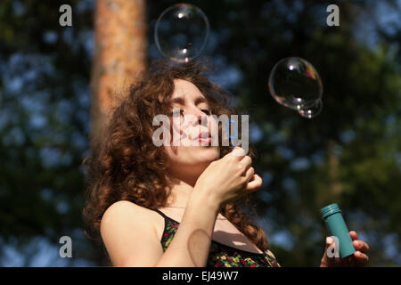 Young Pretty woman blowing soap bubbles in park Banque D'Images