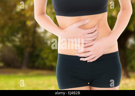 Image composite de la mi section d'une jeune femme fit avec douleur à l'estomac Banque D'Images