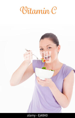 La vitamine C contre la bonne à la femme de manger un bol de salade en position debout Banque D'Images