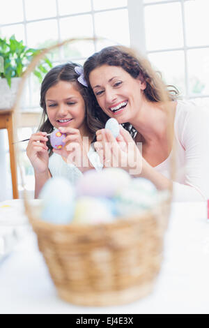 Happy mother and daughter painting Easter eggs Banque D'Images