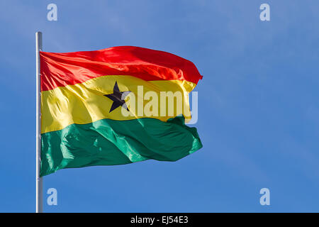Brandissant le drapeau du Ghana est en face de ciel bleu Banque D'Images