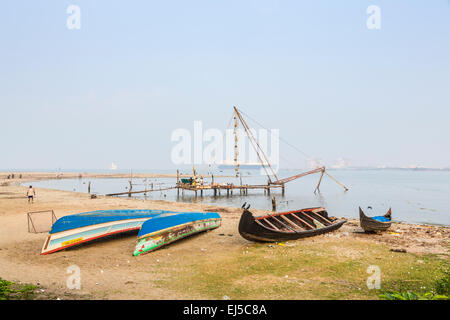 Bateaux de pêche en bois tournée vers le haut en couleur sur la rive par un filet de pêche chinois à fort Cochin, Kerala, Inde du sud Banque D'Images