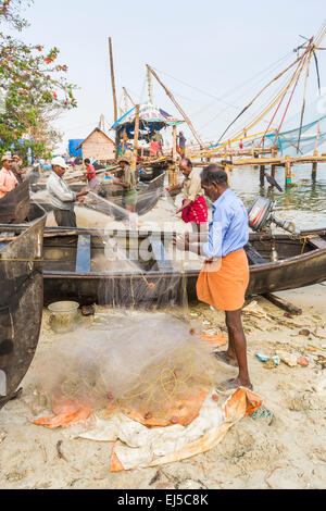 Les pêcheurs qui tendent leurs filets de pêche sur la rive à fort Cochin, Kerala, Inde du sud Banque D'Images