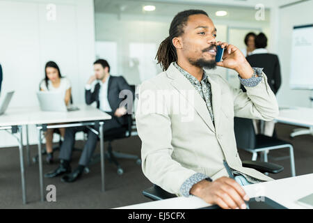 Concepteur graphique beau noir avec des dreadlocks à l'aide d'un numériseur dans un bureau bien rangé, bien éclairé et de l'environnement parler au phon Banque D'Images