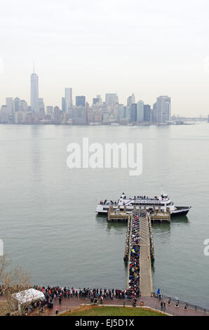 À partir de la Statue de la liberté un jour de pluie, plus de foules d'attente pour le ferry, à l'horizon de Manhattan. Banque D'Images