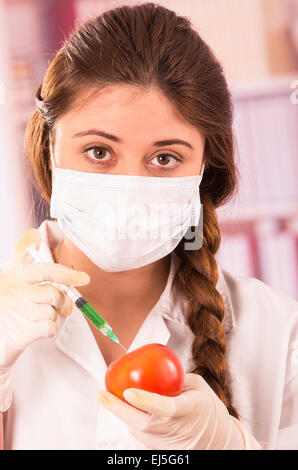 Les jeunes femmes dans une seringue d'injection biologiste tomato Banque D'Images