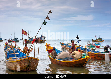 Les pêcheurs vietnamiens sur les bateaux en bois traditionnels au port de pêche de Mui Ne. Mui Ne, la Province de Binh Thuan, Vietnam. Banque D'Images