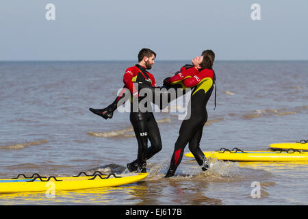 Les bénévoles de RNLI, LifeGuards, s'exercent à la formation de secours et à la récupération en terre sur Ainsdale, Merseyside, plage à marée haute. Surf Life Saving est un sport qui simule des vies sauvées et se compose de différentes courses – natation, pagayage de planche et pagayage de ski. Les sauvetages simulés sont utilisés pour s'exercer à répondre dans différentes conditions. Banque D'Images