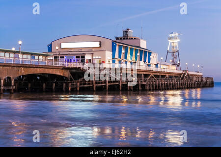 Les lumières de la jetée de nuit reflète dans le sable humide sur la plage. Dorset England UK Europe. Banque D'Images