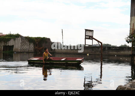 Manille, Philippines. Mar 22, 2015. Un jeune garçon paddles son chemin à travers un vieux terrain de basket dans l'Artex composé. Autour de 175 familles vivent dans l'Artex à Malabon, au nord de Manille. Le domaine de l'habitation a été inondé d'eau taille haute depuis le milieu des années 80. © J Gerard Seguia/Pacific Press/Alamy Live News Banque D'Images