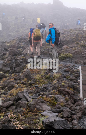 Les promeneurs sur le Tongariro alpine crossing à pied dans des conditions météorologiques extrêmes. La Nouvelle-Zélande. Banque D'Images