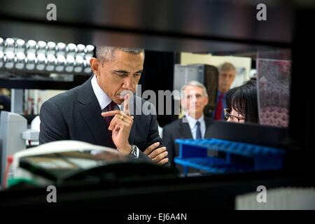 Le président américain Barack Obama est à l'écoute de la Dre Nancy Sullivan, chercheur principal, chef de la Section de recherche de défense biologique, expliquer le candidat vaccin contre Ebola expérimentaux en cours de test sur les humains au cours d'une visite de laboratoire au Centre de recherche sur les vaccins à l'Institut National de la santé le 2 décembre 2014 à Bethesda, Maryland. Le Dr Anthony Fauci, directeur de l'Institut national des allergies et des maladies infectieuses et le Dr Francis Collins, directeur des NIH, regarder en arrière-plan. Banque D'Images