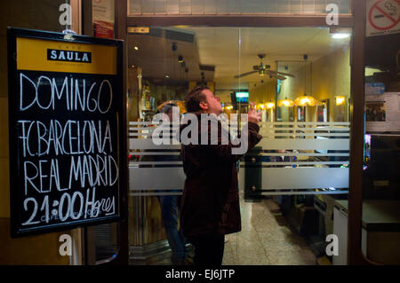 22 mars 2015 - Barcelone, Espagne. À Barcelone un fan de foot regarder la TV à travers la fenêtre d'un bar pendant le match de la Liga entre le FC Barcelone et le Real Madrid CF. Banque D'Images