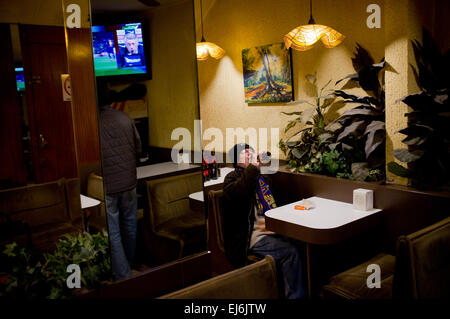 22 mars 2015 - Barcelone, Espagne. Dans un bar à Barcelone un fan du FC Barcelone termine sa bière à la fin du match que l'entraîneur du Real Madrid Carlo Ancelotti donne une conférence de presse à la télévision. Banque D'Images