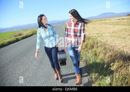 Une femme tenant une guitare sur une route de campagne Banque D'Images