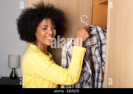 Jeune femme tenant une chemise d'une armoire Banque D'Images