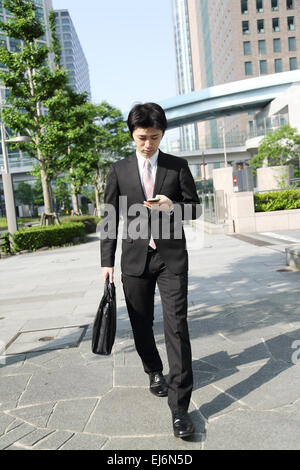 Japanese businessman walking with smartphone Banque D'Images