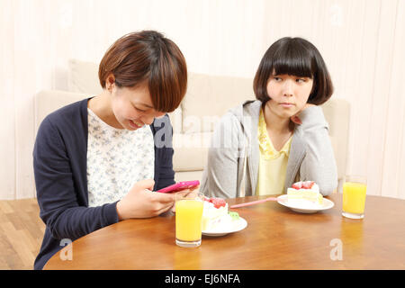 Les jeunes filles japonaises ayant un morceau de gâteau ensemble dans la salle de séjour Banque D'Images