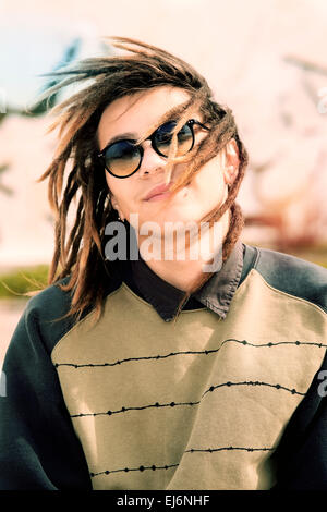 Portrait de jeune homme outdoor avec cheveux rasta dans un concept de vie avec un filtre appliqué à chaud Banque D'Images