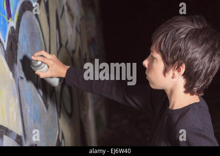 Teen fait des graffiti sur le mur d'un tunnel Banque D'Images