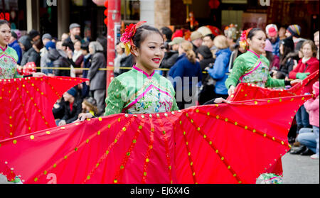 Femme Asiatique pour le transport des grands artistes fans rouge qu'ils prennent part à la parade du Nouvel An lunaire dans le quartier chinois de Vancouver Canada Banque D'Images