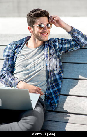 Portrait de jeune homme avec un ordinateur portable sur le banc Banque D'Images