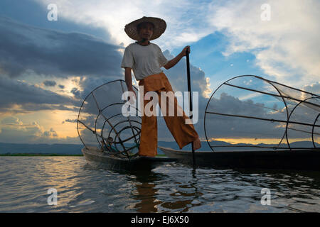 Barque de pêcheur ethnie Intha avec jambe au coucher du soleil sur le lac Inle, l'État de Shan, Myanmar Banque D'Images