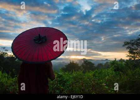 Monk avec parapluie regardant ancien temple et pagode dans la jungle au lever du soleil, Mrauk-U, l'État de Rakhine, au Myanmar Banque D'Images