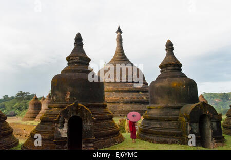 Monk holding parapluie rouge avec Andaw thein-Temple, Mrauk-U, l'État de Rakhine, au Myanmar Banque D'Images