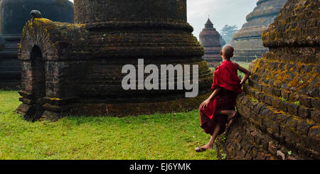 Monk holding parapluie rouge avec Andaw thein-Temple, Mrauk-U, l'État de Rakhine, au Myanmar Banque D'Images