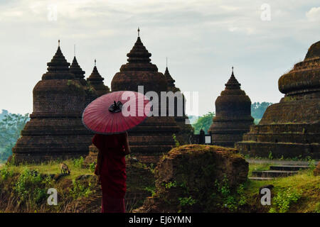 Monk holding parapluie rouge avec Andaw thein-Temple, Mrauk-U, l'État de Rakhine, au Myanmar Banque D'Images