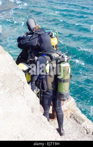 Deux plongeurs se préparent à aller plonger dans la mer à Punta de la aldea, Gran Canaria, Espagne Banque D'Images