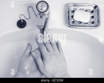 L'homme se lavent les mains sans le savon dans le lavabo au-dessus, teinté bleu image en noir et blanc Banque D'Images