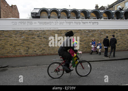 Homme hassidique à vélo avec les enfants déguisés pour Pourim à Stamford Hill 2015 Banque D'Images