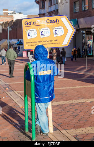 Emploi faiblement rémunéré. Travail non qualifié comme un signe waver. Travailleur ayant un panneau publicitaire pour l'or est égal à l'argent, Derby, England, UK Banque D'Images