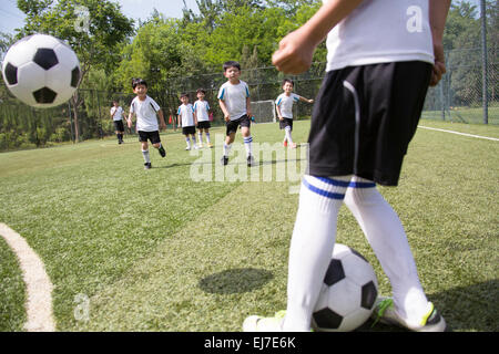 Les garçons jouent au football sur le terrain de jeux Banque D'Images