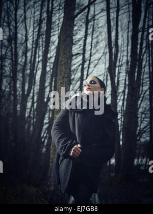 Fashion femme portant un manteau d'hiver et elle pose dans une forêt sombre, froid Un temps pluvieux, les traités de droit pleine longueur Banque D'Images